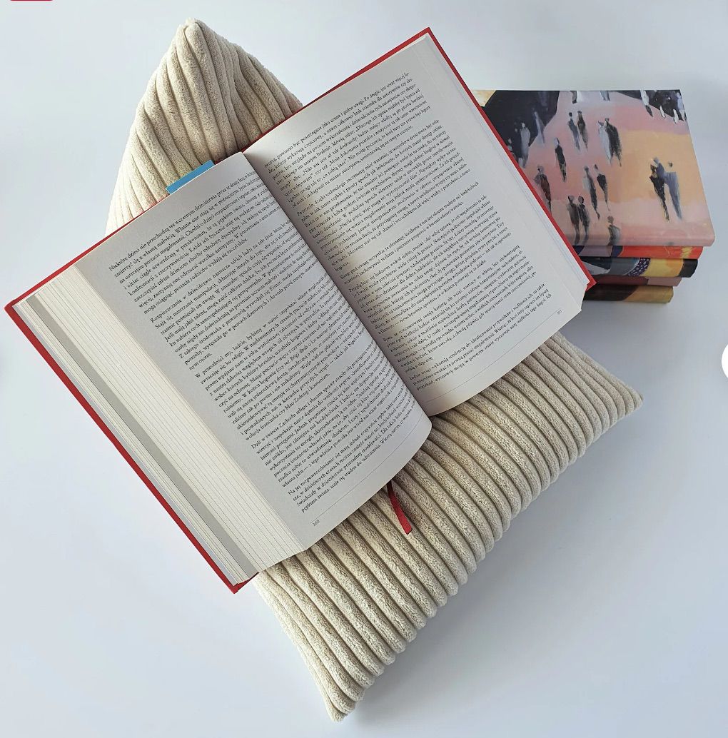 Image of a cream colored corduroy book pillow with an open book on top. 